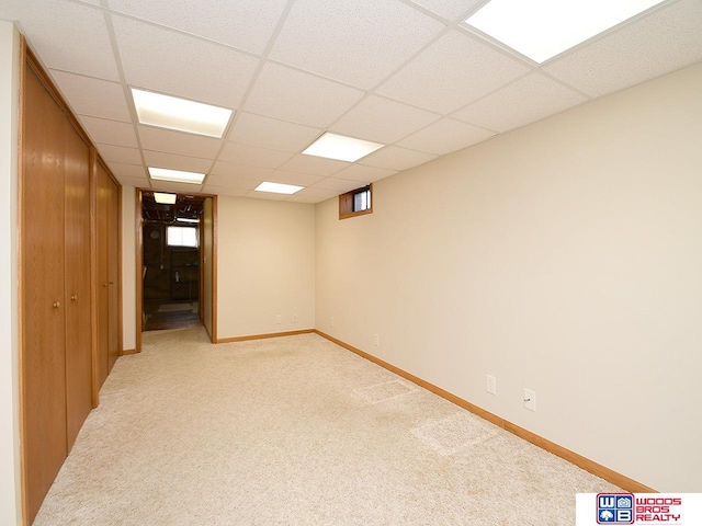 basement featuring a paneled ceiling and light colored carpet