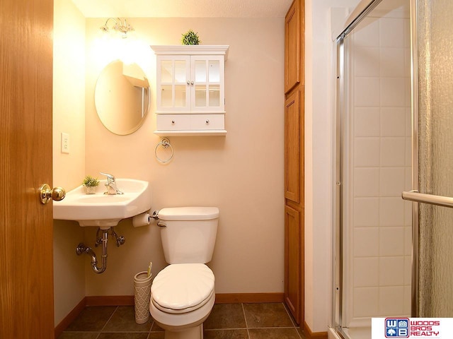 bathroom featuring tile patterned flooring, toilet, a shower with shower door, and sink