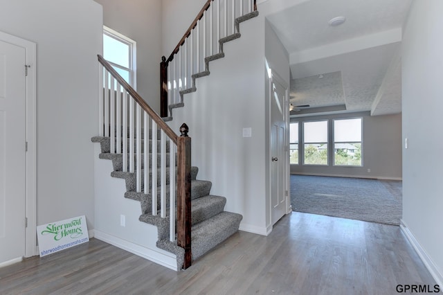 staircase with wood-type flooring, a textured ceiling, and ceiling fan