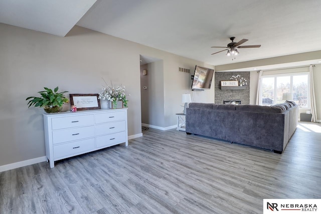 unfurnished living room featuring a fireplace, ceiling fan, and light hardwood / wood-style flooring