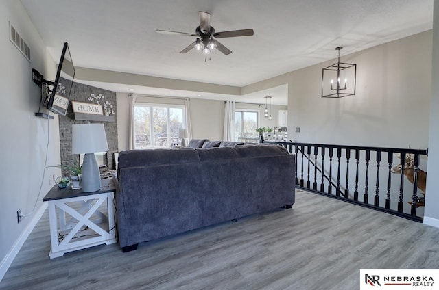 living room with ceiling fan with notable chandelier and wood-type flooring