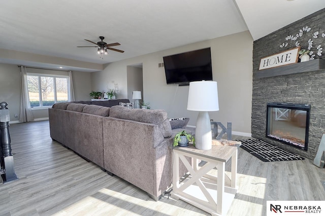 living room with ceiling fan, a fireplace, and light hardwood / wood-style flooring