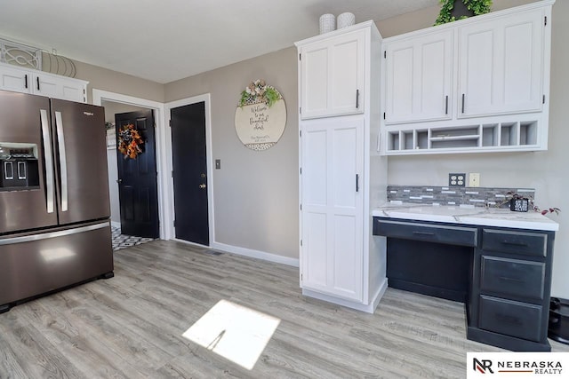 kitchen featuring white cabinets, backsplash, light wood-type flooring, and stainless steel refrigerator with ice dispenser