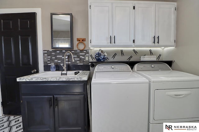 washroom with washing machine and clothes dryer, cabinets, and sink