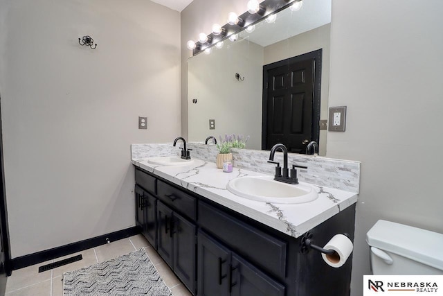 bathroom with toilet, vanity, and tile patterned floors