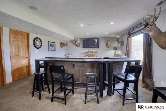 bar with light colored carpet and a textured ceiling