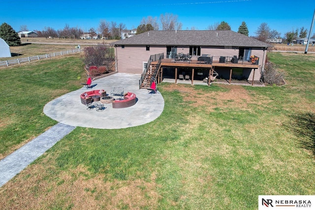 rear view of property with a lawn, a patio area, a deck, and an outdoor fire pit