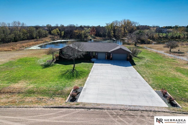 view of front of house with a front yard, a water view, and a garage