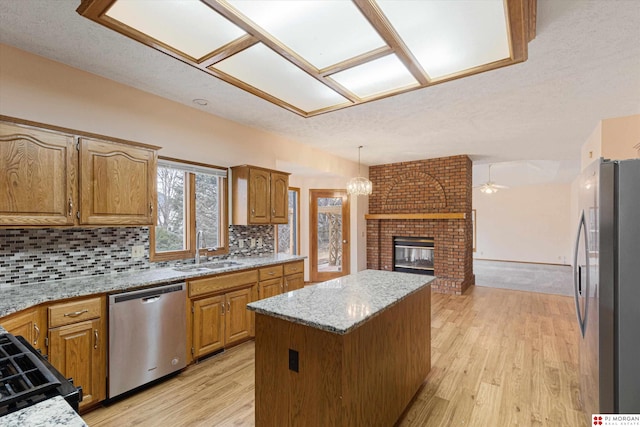 kitchen featuring decorative backsplash, stainless steel appliances, sink, a fireplace, and a kitchen island