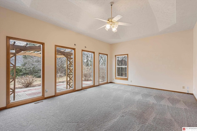 carpeted empty room featuring ceiling fan, a textured ceiling, and a tray ceiling