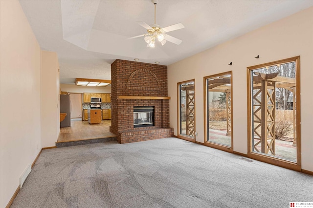 unfurnished living room with ceiling fan, light colored carpet, and a fireplace