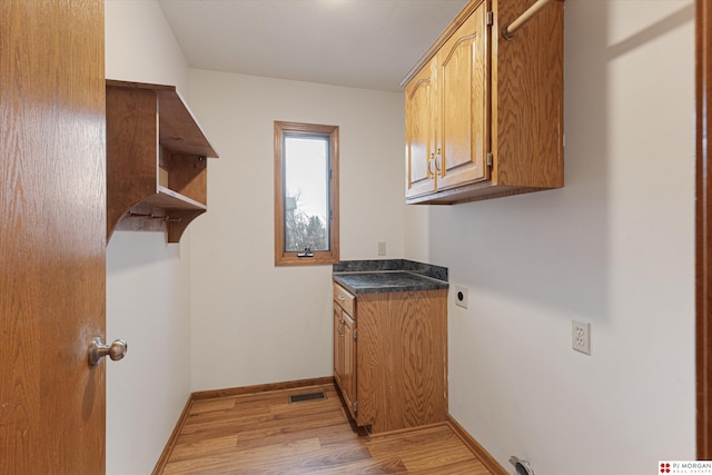 laundry room featuring hookup for an electric dryer, cabinets, and light hardwood / wood-style flooring