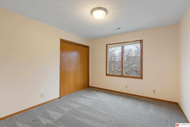 unfurnished bedroom featuring carpet, a textured ceiling, and a closet