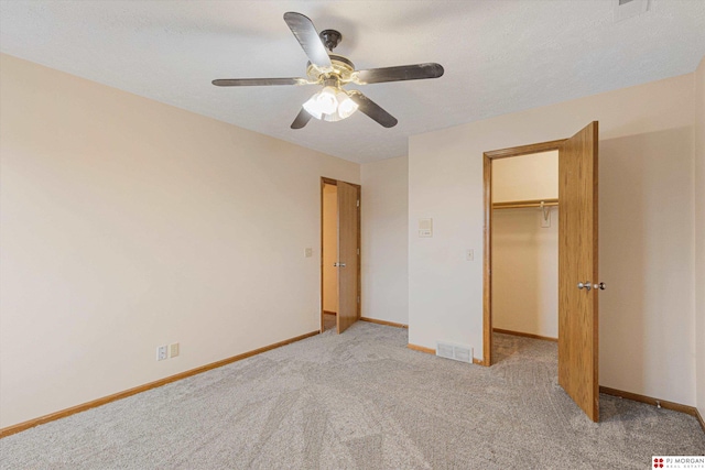 unfurnished bedroom featuring ceiling fan, light colored carpet, a spacious closet, and a closet