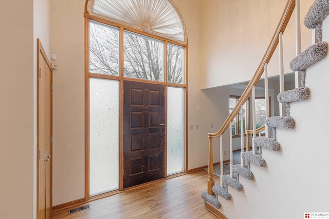 entryway with light hardwood / wood-style floors and a towering ceiling