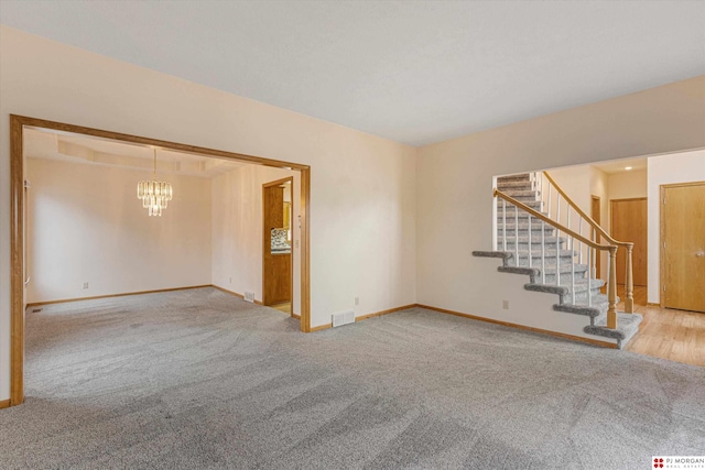 carpeted spare room with an inviting chandelier