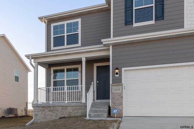 view of front of home with covered porch, a garage, and cooling unit