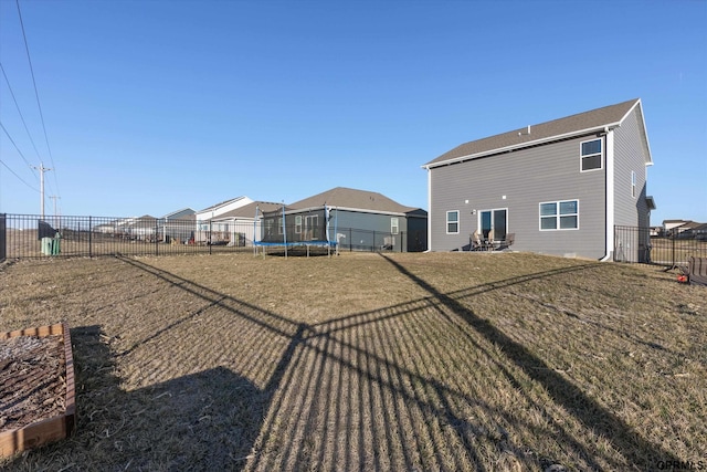 rear view of house with a yard and a trampoline