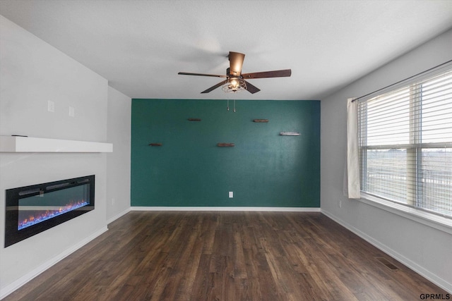 unfurnished living room featuring ceiling fan and dark wood-type flooring