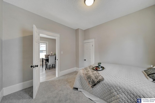 bedroom with a textured ceiling and light colored carpet