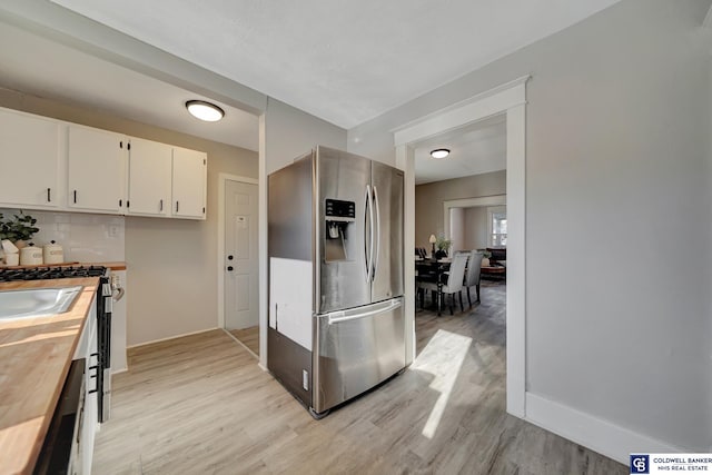 kitchen with light wood-type flooring, backsplash, dishwasher, stainless steel fridge with ice dispenser, and white cabinetry