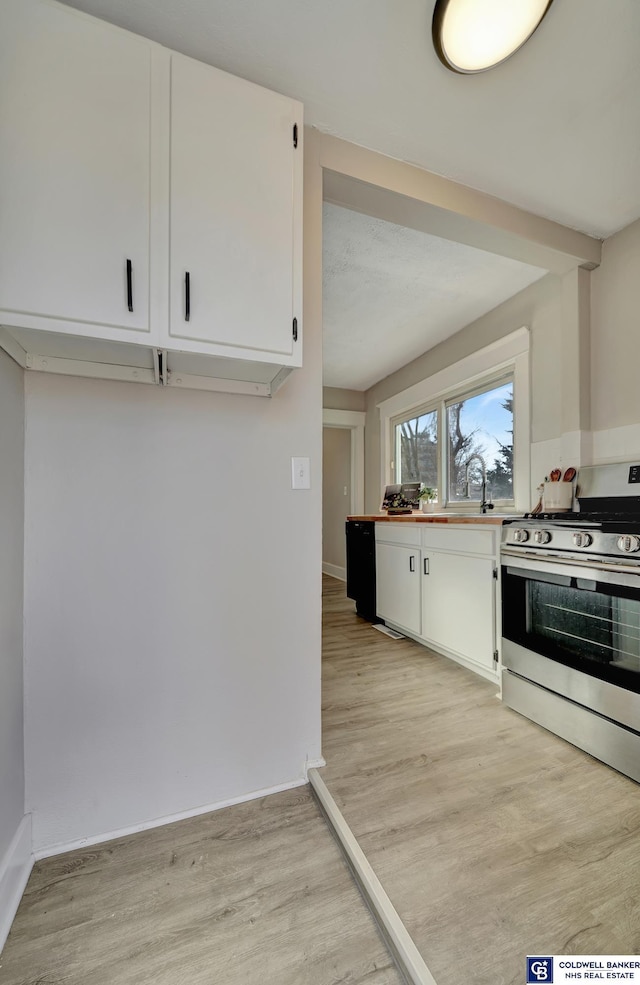 kitchen with stainless steel electric stove, white cabinetry, sink, and light hardwood / wood-style floors