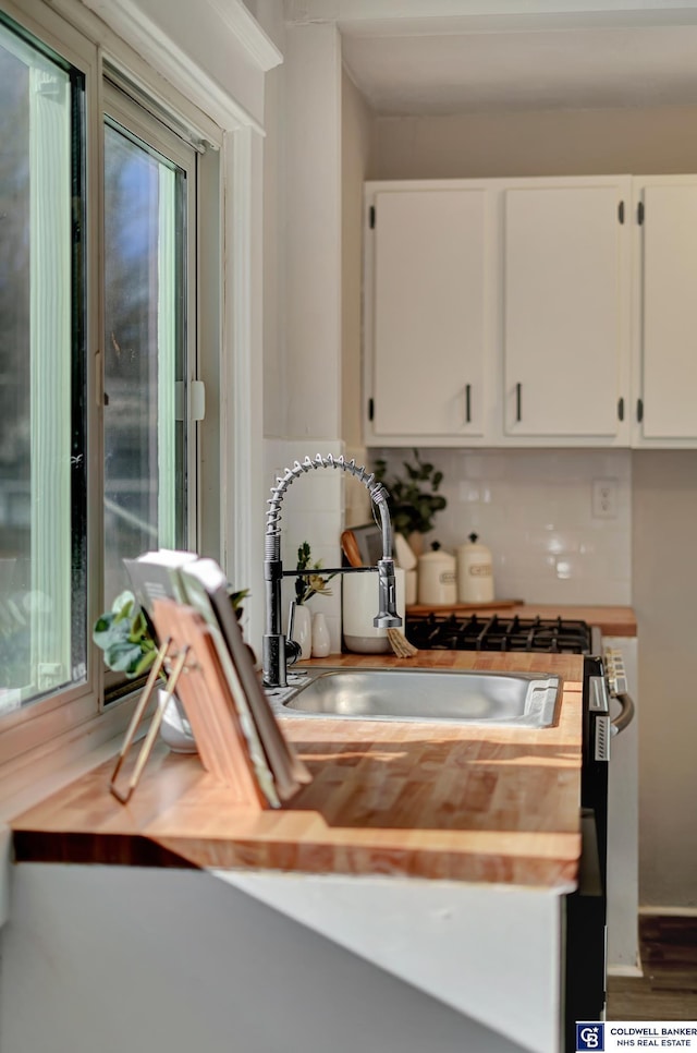 kitchen featuring white cabinets, a healthy amount of sunlight, backsplash, and butcher block counters