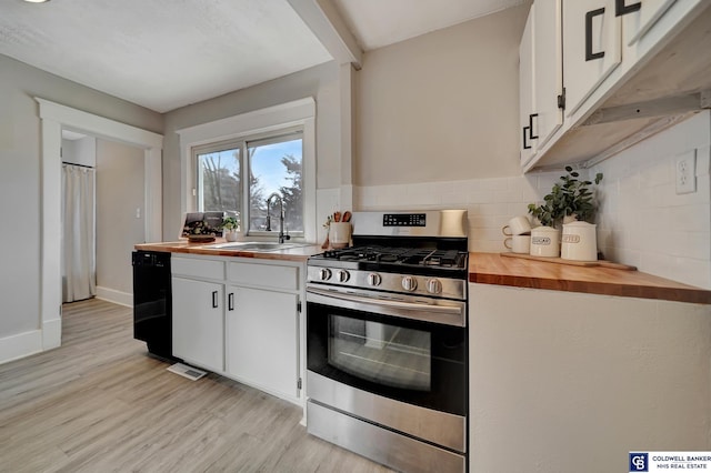 kitchen with butcher block counters, white cabinetry, sink, and stainless steel range with gas stovetop