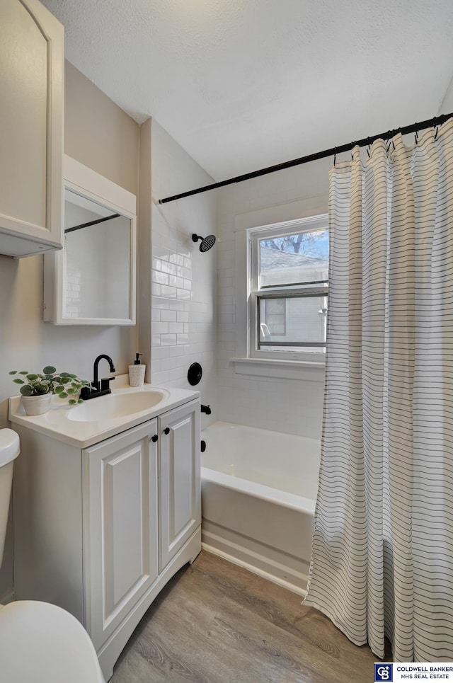 full bathroom featuring shower / bath combination with curtain, vanity, a textured ceiling, wood-type flooring, and toilet