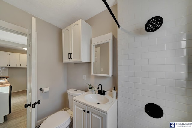 bathroom with hardwood / wood-style flooring, vanity, toilet, and a textured ceiling