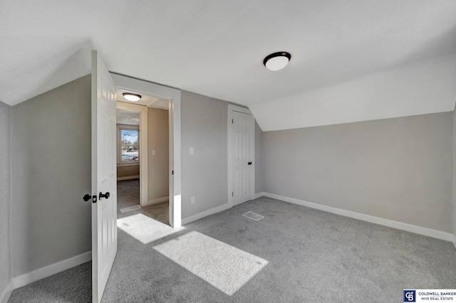 additional living space with light colored carpet and vaulted ceiling