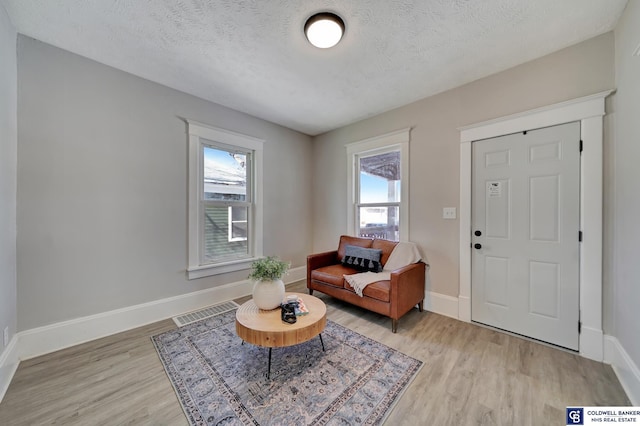 sitting room with light wood-type flooring and a textured ceiling