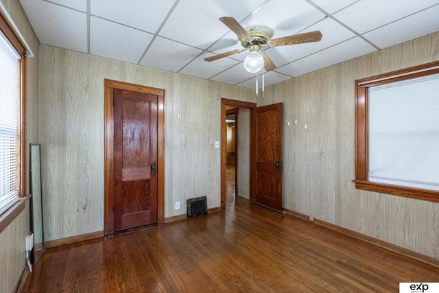 unfurnished bedroom with hardwood / wood-style flooring, ceiling fan, and a drop ceiling