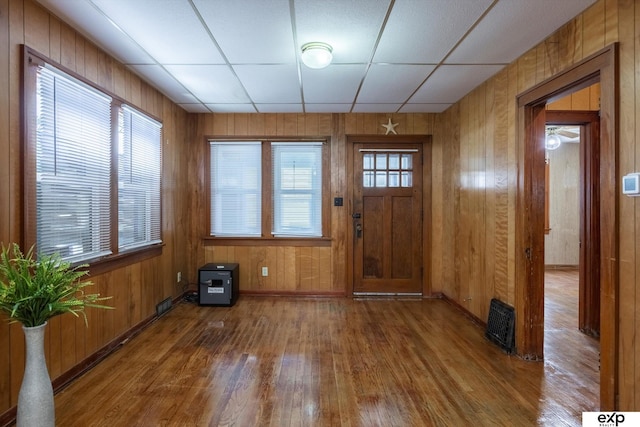 entryway featuring a paneled ceiling, wooden walls, plenty of natural light, and hardwood / wood-style flooring