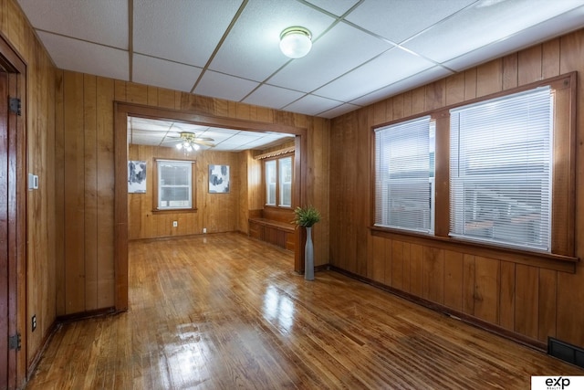 spare room with wood-type flooring, ceiling fan, and wood walls