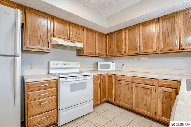 kitchen with white appliances, light tile patterned floors, and a textured ceiling