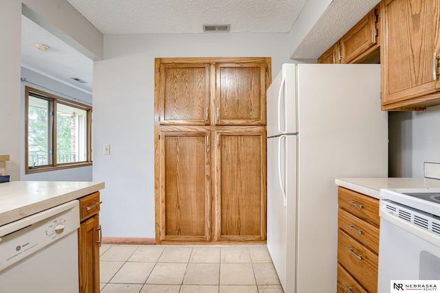 kitchen with white appliances, light tile patterned floors, and a textured ceiling