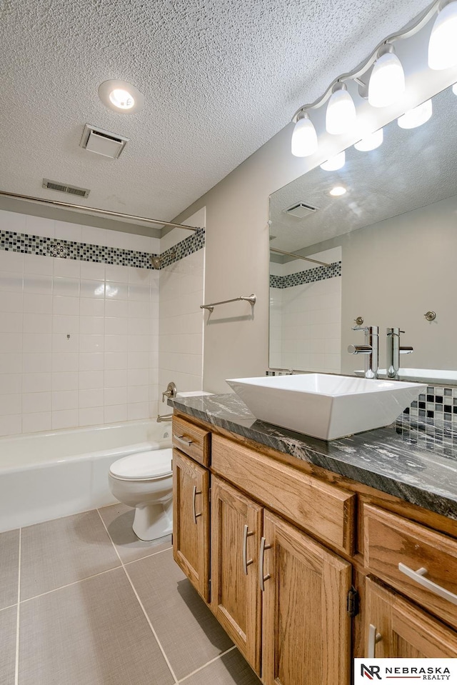 full bathroom featuring a textured ceiling, toilet, vanity, and tile patterned flooring