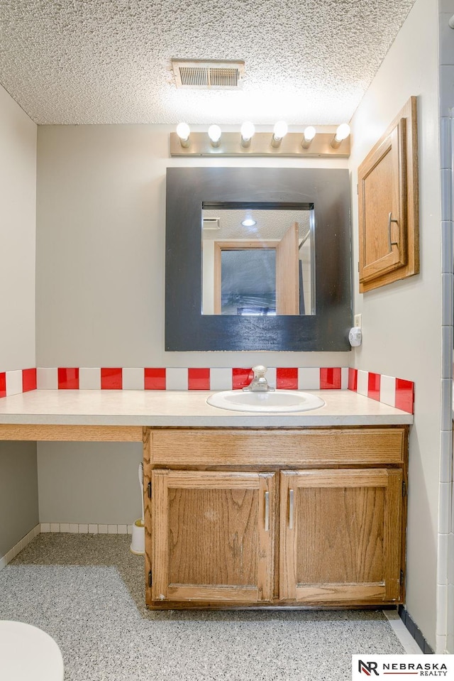 bathroom featuring a textured ceiling and vanity