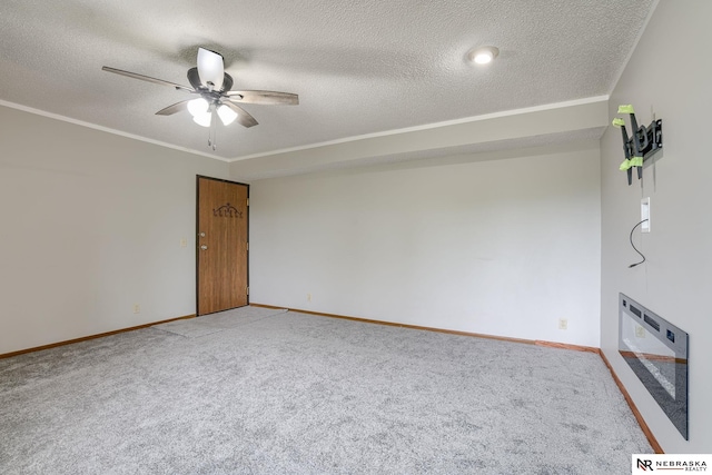 unfurnished living room with a textured ceiling, carpet floors, ceiling fan, and ornamental molding