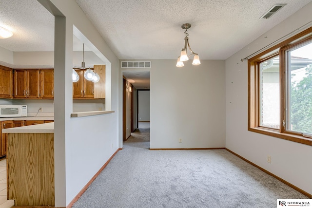 kitchen with light colored carpet, hanging light fixtures, and a textured ceiling