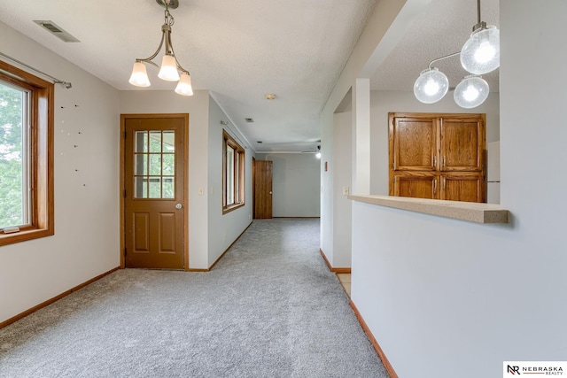 foyer entrance with a chandelier, a healthy amount of sunlight, and light colored carpet