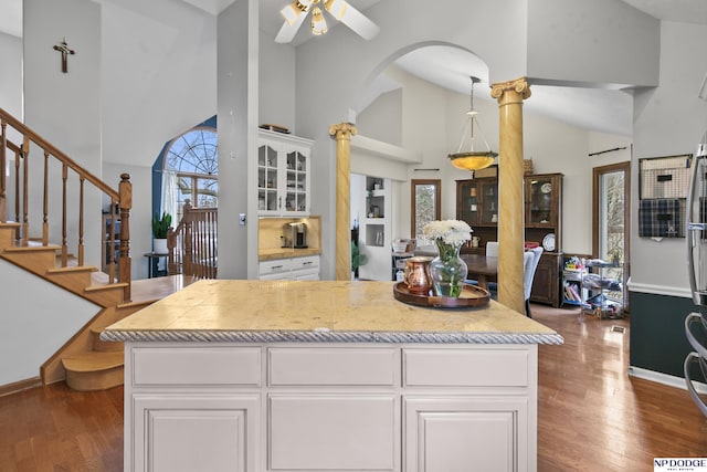 kitchen featuring a towering ceiling, decorative columns, ceiling fan, dark hardwood / wood-style floors, and white cabinetry