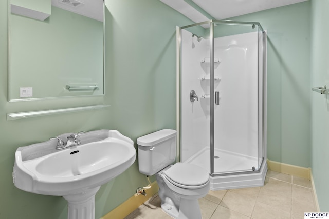 bathroom with tile patterned floors, sink, a shower with shower door, and toilet