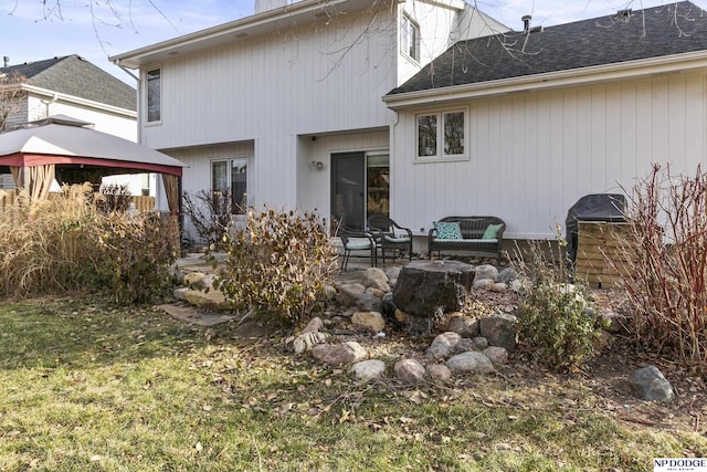 back of property with a gazebo, a patio area, and a lawn