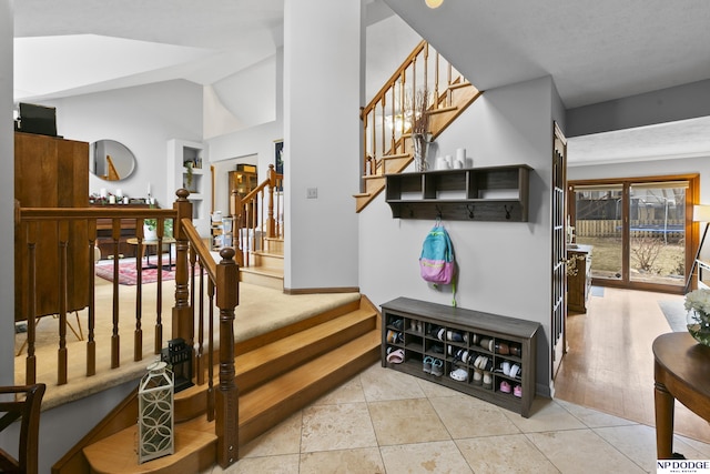 stairway with tile patterned flooring and lofted ceiling