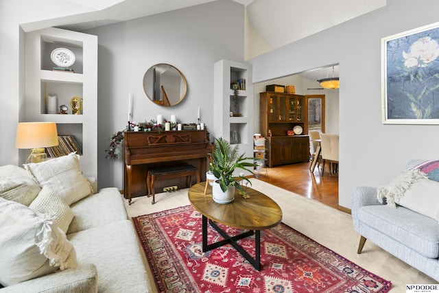 living room with built in shelves and lofted ceiling