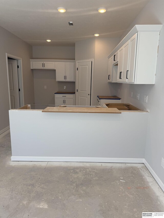 kitchen featuring unfinished concrete floors, recessed lighting, visible vents, baseboards, and white cabinetry