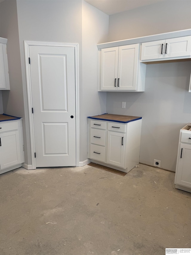 kitchen with white cabinets and unfinished concrete flooring