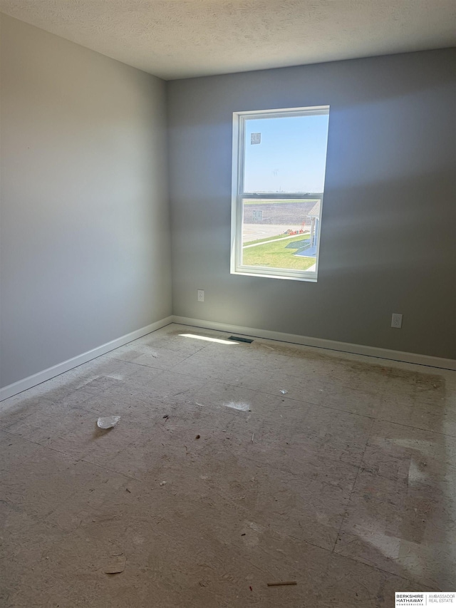 spare room with a textured ceiling and baseboards